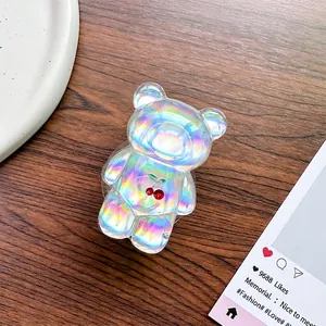 Macro shot of holographic bear phone grip with red cherry print on a wooden desk