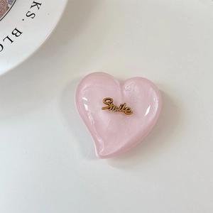 Gros plan d'un support de téléphone coeur rose pailleté avec lettrage Smile doré
