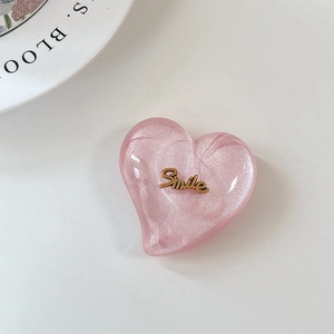 Gros plan du support de téléphone cœur pailleté rose avec emblème Smile doré