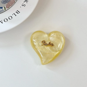 Détail du support de téléphone cœur à paillettes jaunes avec texte Smile métallique