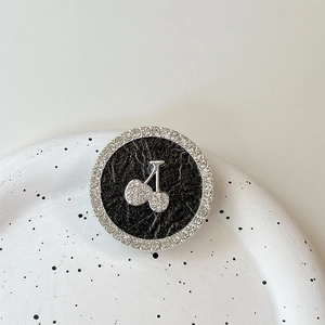 Close-up of rhinestone cherry phone grip holder with sparkling gems on black leather base