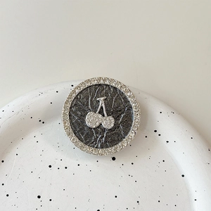 Detailed view of a round rhinestone cherry phone grip with black leather texture finish