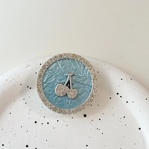 Detail of rhinestone round cherry phone grip with silver cherry motif and blue leather base