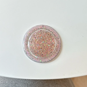 Close-up of a round MagSafe phone grip with colorful holographic glitter and sequins