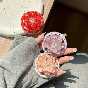 Close-up of three 3D floral phone socket grips in red, purple, and champagne pink hues