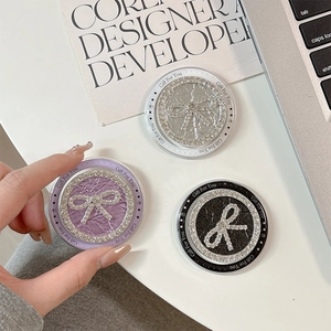 Round phone grip stands with rhinestone bow design in silver, purple, and black finishes