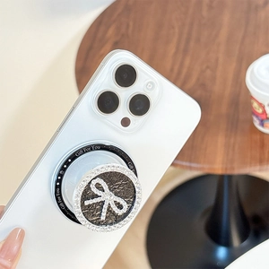 Detailed view of luxury rhinestone bow phone grip attached to a white smartphone