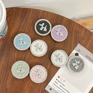 Rhinestone balloon dog phone grip socket in various colors on a dark wooden table