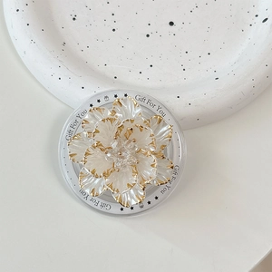 Detail of a floral popsocket with translucent white petals and golden trim for phones
