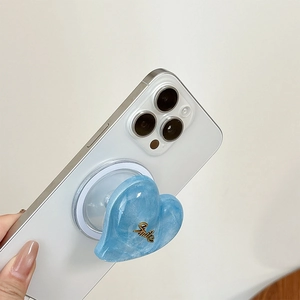 Blue marble heart MagSafe phone grip with gold Smile text on a white smartphone