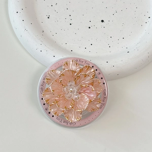 Detail of a 3D pink floral phone grip with gold edges and crystal center on a tray