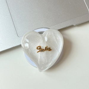 Macro shot of white glitter heart MagSafe phone stand with gold Smile lettering details