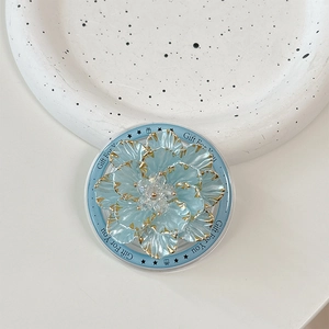 Detail of blue floral pop socket with gold edges and crystal center on ceramic tray