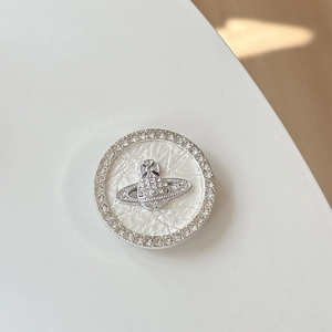 Detailed view of silver rhinestone phone grip with central Saturn orb logo and leather texture