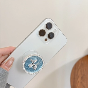 Macro detail of rhinestone-studded silver balloon dog phone grip on light blue leather