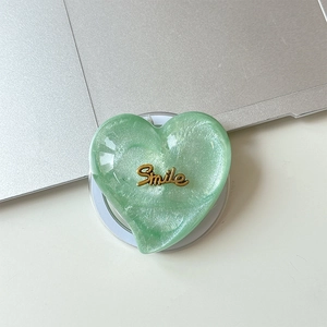 Macro detail of heart-shaped glitter phone grip with a golden Smile metallic lettering