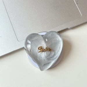 Detail of silver glitter heart MagSafe phone stand with golden Smile text engraving