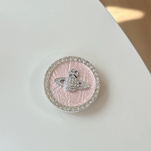 Detail view of pink leather phone grip featuring a rhinestone encrusted planet logo