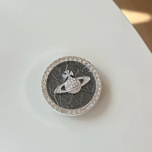 Detailed close-up of a silver planet phone grip with sparkling rhinestones and saturn logo