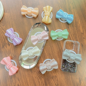 Magnetic glittery bow phone grip holder in various vibrant candy colors on wooden surface