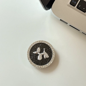 Close-up of rhinestone balloon dog phone grip on black leather texture background