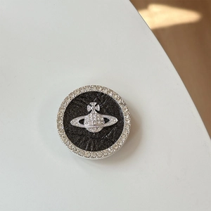 Macro detail of rhinestone planet phone grip with silver Saturn orb on black leather
