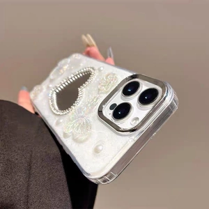 Dettaglio custodia iPhone con cuore di strass, farfalla 3D e perle su base bianca