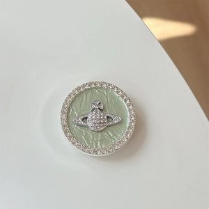 Macro detail of planet emblem phone grip with green leather base and crystal border