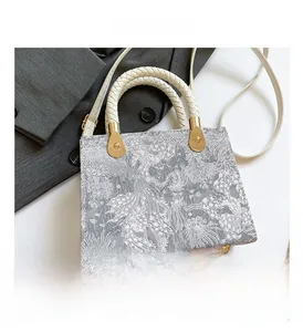 Detail of silver-grey floral jacquard crossbody bag with woven leather handles