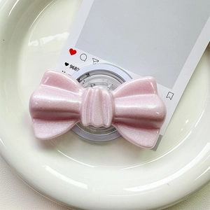 Close-up of pink glitter bow magnetic phone grip with pearl finish on ceramic tray