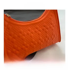 Detail of bright orange baguette bag with 3D embossed diamond texture and metal zipper