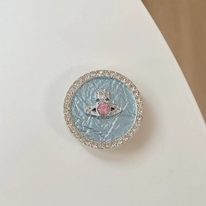 Detail of round rhinestone phone socket featuring pink gem saturn orb on blue background