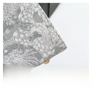 Close-up of grey floral jacquard fabric with a gold metal stud on a handbag detail
