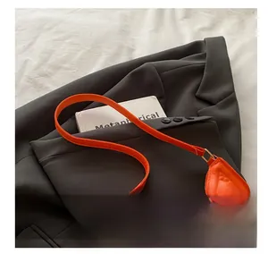 Detail of vibrant orange baguette bag with geometric triangle embossing on grey suit
