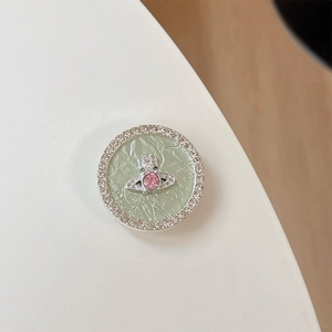 Detail of rhinestone round phone grip featuring silver planet orb design and pink gem
