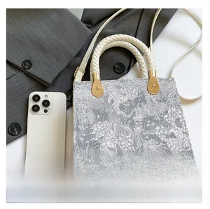 Detailed size comparison of the jacquard handbag showing a smartphone for scale reference