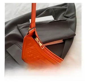 Macro detail of smooth golden zipper and quilted embossed pattern on orange shoulder bag