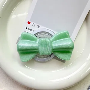 Detailed close-up of mint green glitter bow magnetic phone grip on a white ceramic plate