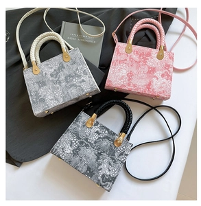 Detailed view of woven handles and patterned texture on gray, pink and black handbags
