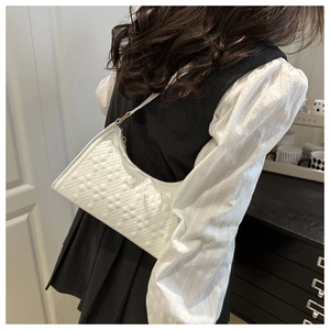 Detail of white quilted crescent bag showing elegant diamond stitching and gold hardware