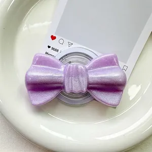 Macro shot of purple glitter bow magnetic phone grip on a white ceramic tray