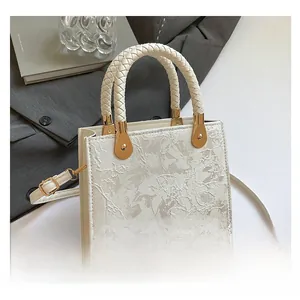 Close-up of white floral lace embroidery on a luxury handbag with gold hardware