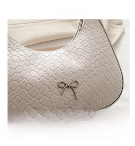Détail d'un sac blanc à motif crocodile avec une boucle en forme de nœud argenté