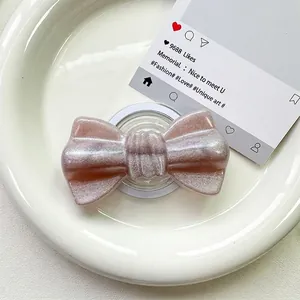 Close-up of glittery bow-shaped magnetic phone grip on a decorative white plate