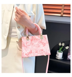 Detail of pink crossbody bag with embossed floral texture and woven handle in home setting