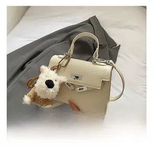 Détail du sac à main plissé crème avec boucle métallique et pendentif peluche chien
