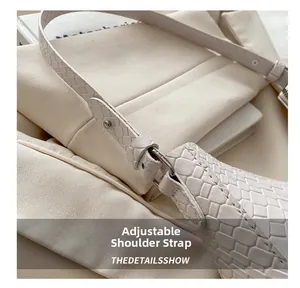 Détail du sac crème avec texture tissée et boucle en métal argenté réglable sur la sangle