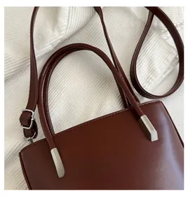 Detail of dark brown leather bucket bag with silver metal handle hardware and shoulder strap