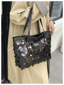 Detail of black sequined tote bag featuring a Creative Cat tag and long shoulder strap