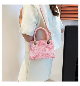 Detail of pink embroidered floral handbag with woven handles and gold metal hardware